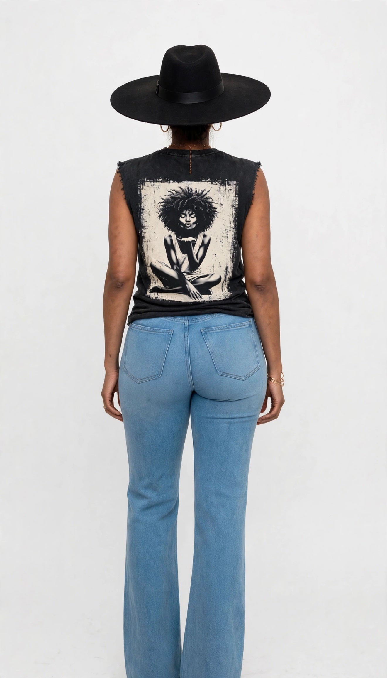 Back view of Erica modeling the black sleeveless cutoff tee with a large afro kiss graphic